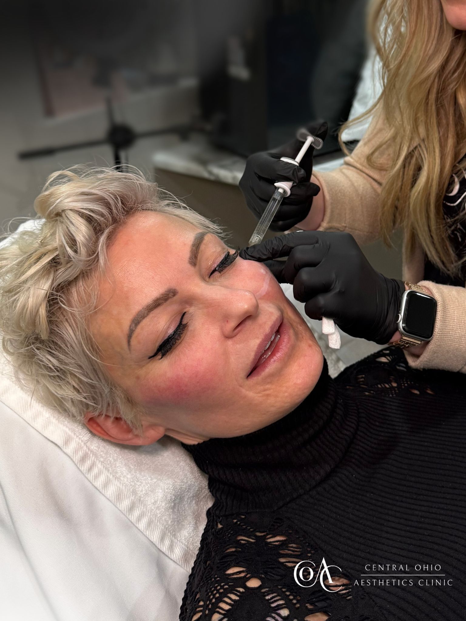 A woman receiving eyebrow shaping from a professional in a beauty salon setting.