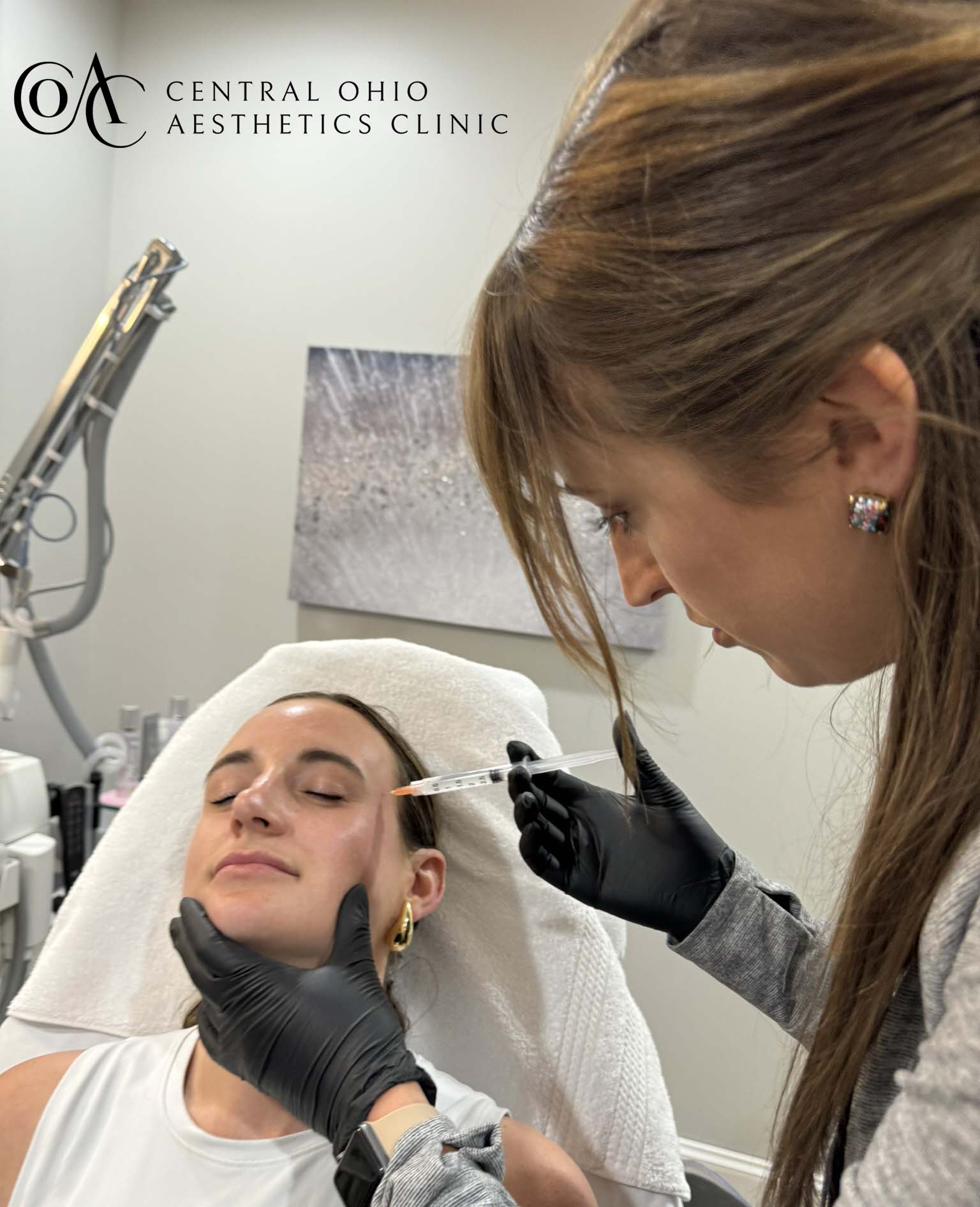 A woman receiving facial treatment from a doctor in a clinical setting.
