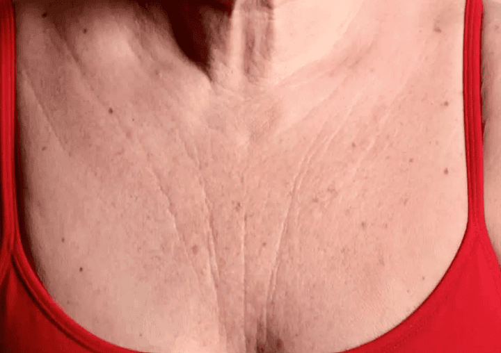 A woman wearing a red bra, showcasing her large chest in a confident pose.
