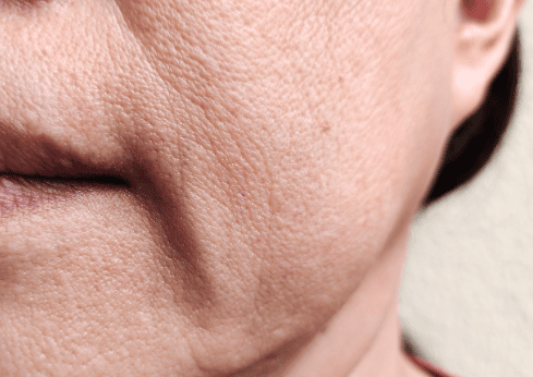 A close-up of a woman's face showing wrinkles, wearing a bright red shirt, conveying wisdom and experience.